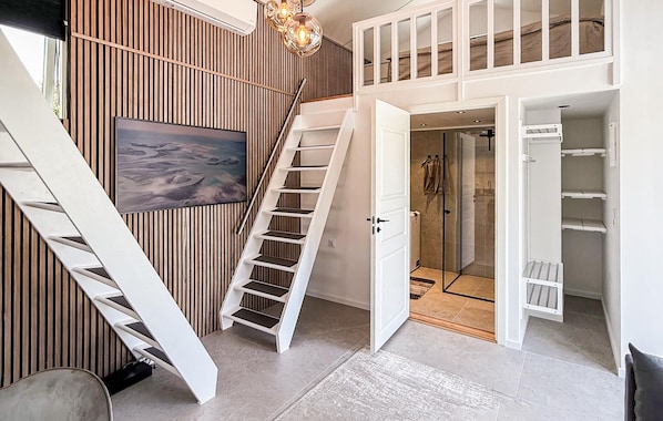 A modern interior with a staircase, a glass shower, and a mounted artwork.
