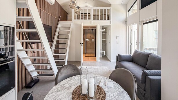 Interior moderno com área de jantar, escada, quarto no mezanino e sala de estar.