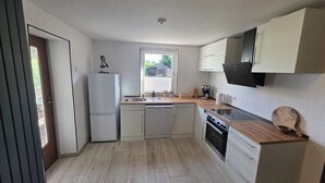 Eine kleine Küche mit Kühlschrank, Spüle, Herd und einer Holzarbeitsplatte.