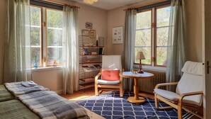 A cozy room with a bed, two chairs, a small table, a bookshelf, and large windows with curtains. - 3 bedroom nice apartment in Fjällbacka (Fjällbacka)