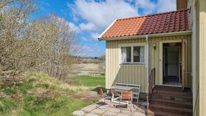 A small, single-story building with a tiled roof and a small porch with a table and chairs. - 3 bedroom nice apartment in Fjällbacka (Fjällbacka)