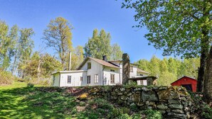 A rustic house with a stone wall and a red barn in a forested area. - 3 bedroom lovely home in Håverud (Håverud)