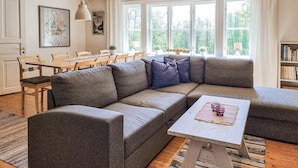 A modern living room with a sectional sofa, a dining table, and large windows. - 3 bedroom lovely home in Håverud (Håverud)