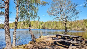 A lakeside picnic area with a wooden bench and a picnic table. - 3 bedroom lovely home in Håverud (Håverud)