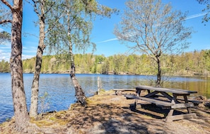 En picknickplats vid sjön med en träbänk och ett picknickbord.