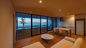 Un salon moderne doté d’une grande porte-fenêtre coulissante donnant sur un balcon avec vue sur la mer.