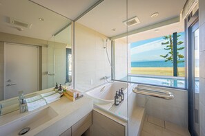 A modern bathroom with a large mirror, a bathtub, and a shower.