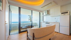 Une cuisine moderne avec vue sur la mer, un coin repas avec une chaise, et un balcon avec une table et des chaises.