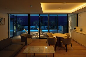 Una sala de estar moderna con pared de vidrio, piscina y comedor.