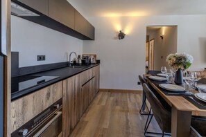 Eine moderne Küche mit Holzschränken, einer schwarzen Arbeitsplatte und einem Essbereich mit einem Holztisch, gedeckt für vier Personen.
