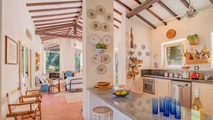 Een keuken met een centraal kookeiland, barstoelen en een zithoek met een bank en stoelen.