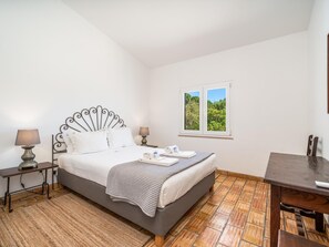 Ein Schlafzimmer mit Bett, Nachttischen, einem Fenster mit Aussicht und einem Holztisch.