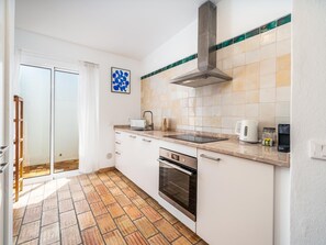 Eine kleine Küche mit Einbauofen, Toaster und Kaffeemaschine auf der Arbeitsplatte.