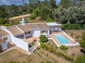 Ein zweistöckiges Haus mit Swimmingpool, umgeben von Grünflächen und Bäumen.