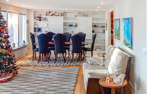A modern living room with a dining area, a Christmas tree, and a bookshelf filled with various items. - Lovely home in Gränna with sauna (Gränna)