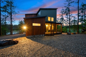 Un bâtiment moderne à deux étages, doté d’une façade en bois, d’un porche couvert et offrant une vue sur une zone boisée.