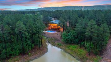 Un chalet entouré de forêt, doté d’une piscine et bordé par une rivière.