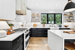 A modern kitchen with white cabinetry, a central island, and a large window.