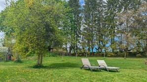 Eine Rasenfläche mit zwei Liegestühlen und einem Baum.