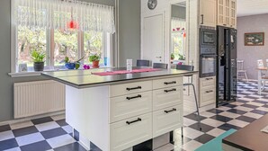 Eine Küche mit Kochinsel, weißen Schränken, einem schwarzen Kühlschrank und einem Schachbrettboden.