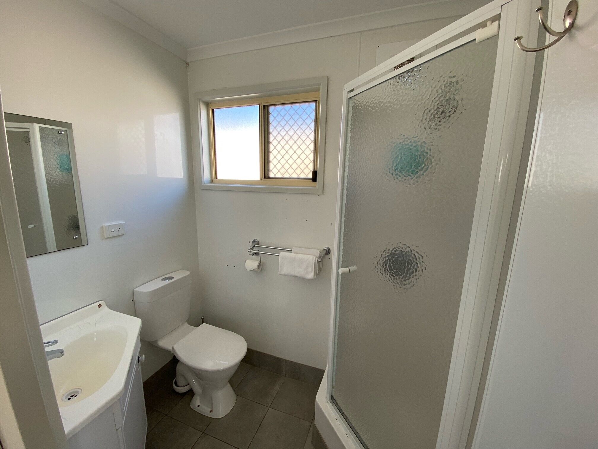 Un baño con inodoro, lavamanos y ventana.