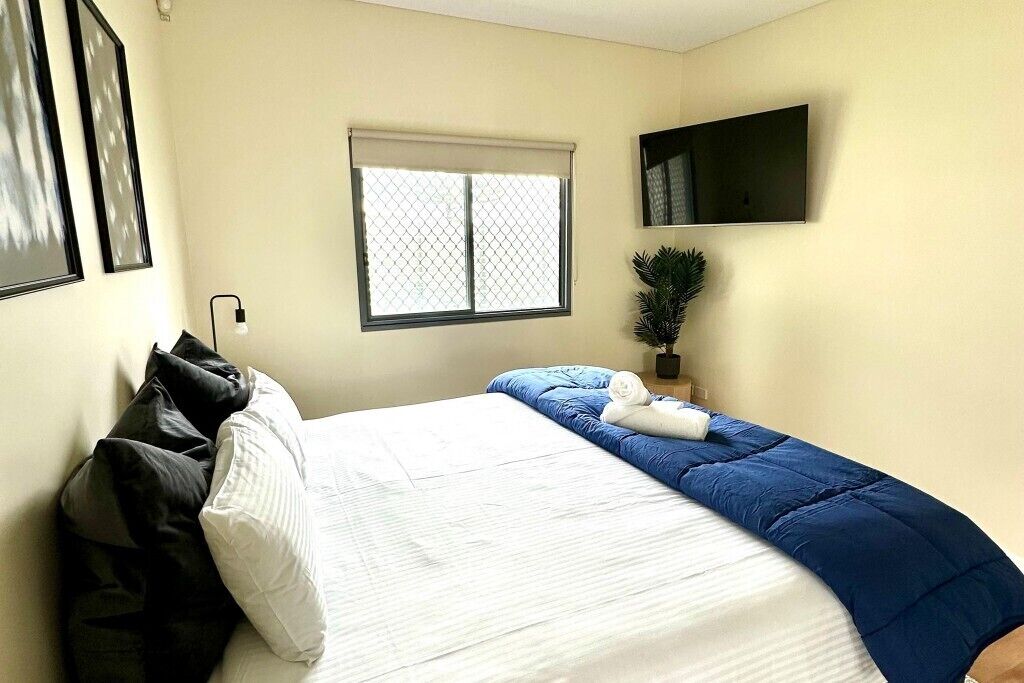 Ein Hotelzimmer mit Bett, Fenster mit Aussicht, Flachbildfernseher und Topfpflanze.