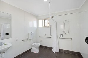 A modern bathroom with a toilet, sink, shower, and grab bars. - Christies Beach Tourist Park (Christies Beach)