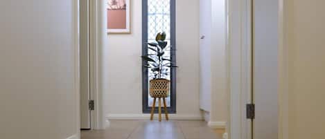 Un pasillo con una puerta, un cuadro enmarco y una planta en maceta.