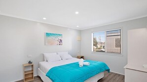 Un dormitorio moderno con una cama, una mesita de noche, una ventana con persianas y una obra de arte colgada en la pared.