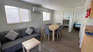 Un espacio habitable compacto con sofá, una mesa de comedor y una kitchenette.