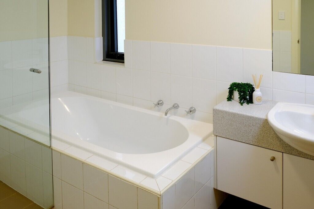 Un bagno con una vasca, un lavandino e uno specchio.