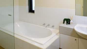 A bathroom with a bathtub, a sink, and a mirror.