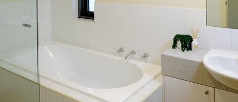Une salle de bain avec une baignoire, un lavabo et un miroir.