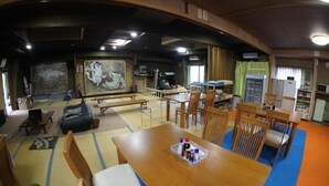 Una habitación tradicional japonesa con suelo de tatami, una mesa baja con una bandeja de objetos y un comedor con sillas de madera.