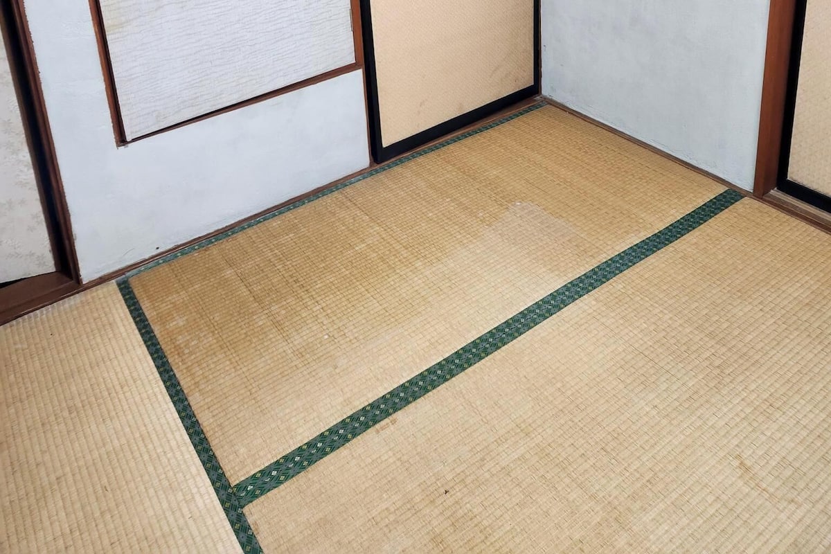 Ein Zimmer mit Tatami-Böden, einer Schiebetür und einer Wand mit strukturierter Oberfläche.
