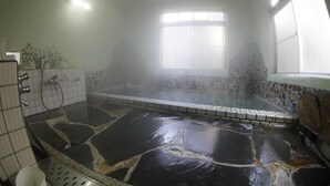 Un baño con suelo de piedra, ventana y zona de ducha.