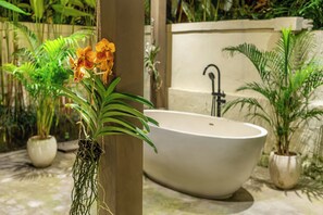 A bathroom with a freestanding bathtub, a sink, and various potted plants. - Orchid Garden Villa (Ubud)
