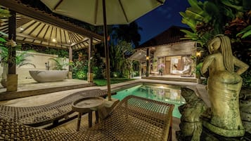 Zona junto a la piscina con sillas de descanso, un jacuzzi y una estatua.