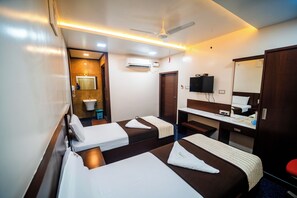 A hotel room with two beds, a desk, a mirror, an air conditioning unit, and a television. - V V Residency (Thanjavur)