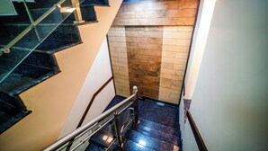 A staircase with glass railings and a wooden door at the bottom. - V V Residency (Thanjavur)