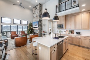 A spacious living area with a large island, wooden cabinets, and a stone accent wall. - Deer Valley East Perfect for Groups | 5BR w/ Game Room + Hot Tub (Heber City)