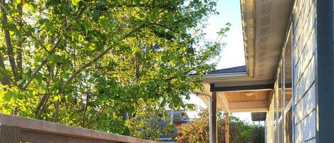 A wooden deck with a railing, a covered area, and flower planters.