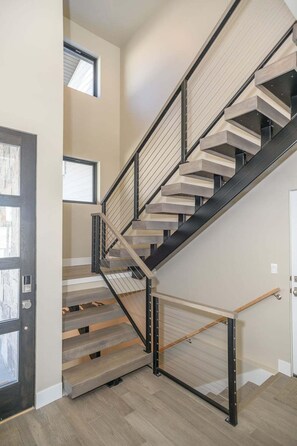 Eine moderne Treppe mit Holzvertäfelung und schwarzen Metallgeländern, die zu einer oberen Etage führt.