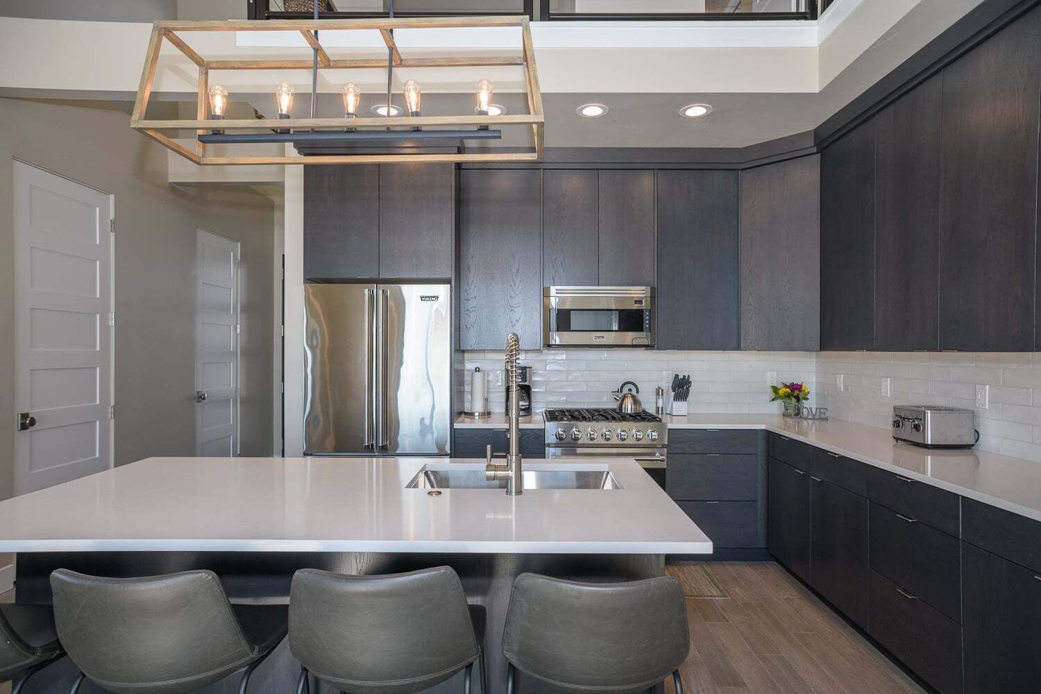 Una cocina moderna con una isla grande, electrodomésticos de acero inoxidable y muebles oscuros.
