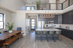 Eine moderne Küche mit Kochinsel, dunklen Schränken und einem Essbereich mit Holztisch und Stühlen.