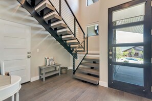 Eine Treppe mit dunkler Metallreling, einer weißen Tür und einer Sitzbank mit Kissen.