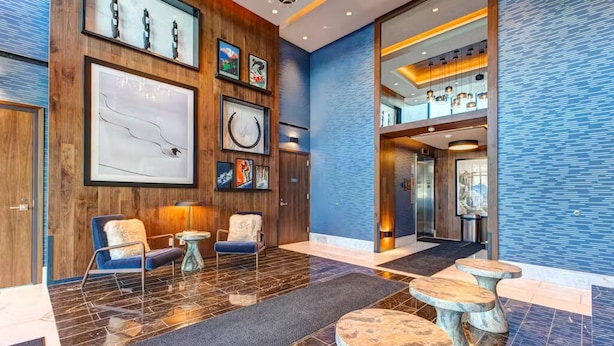 A lobby with wooden paneling, framed artwork, and a seating area with round tables.