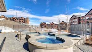 A pool area with a circular design, surrounded by a fence, and adjacent to a building with a sloped roof.