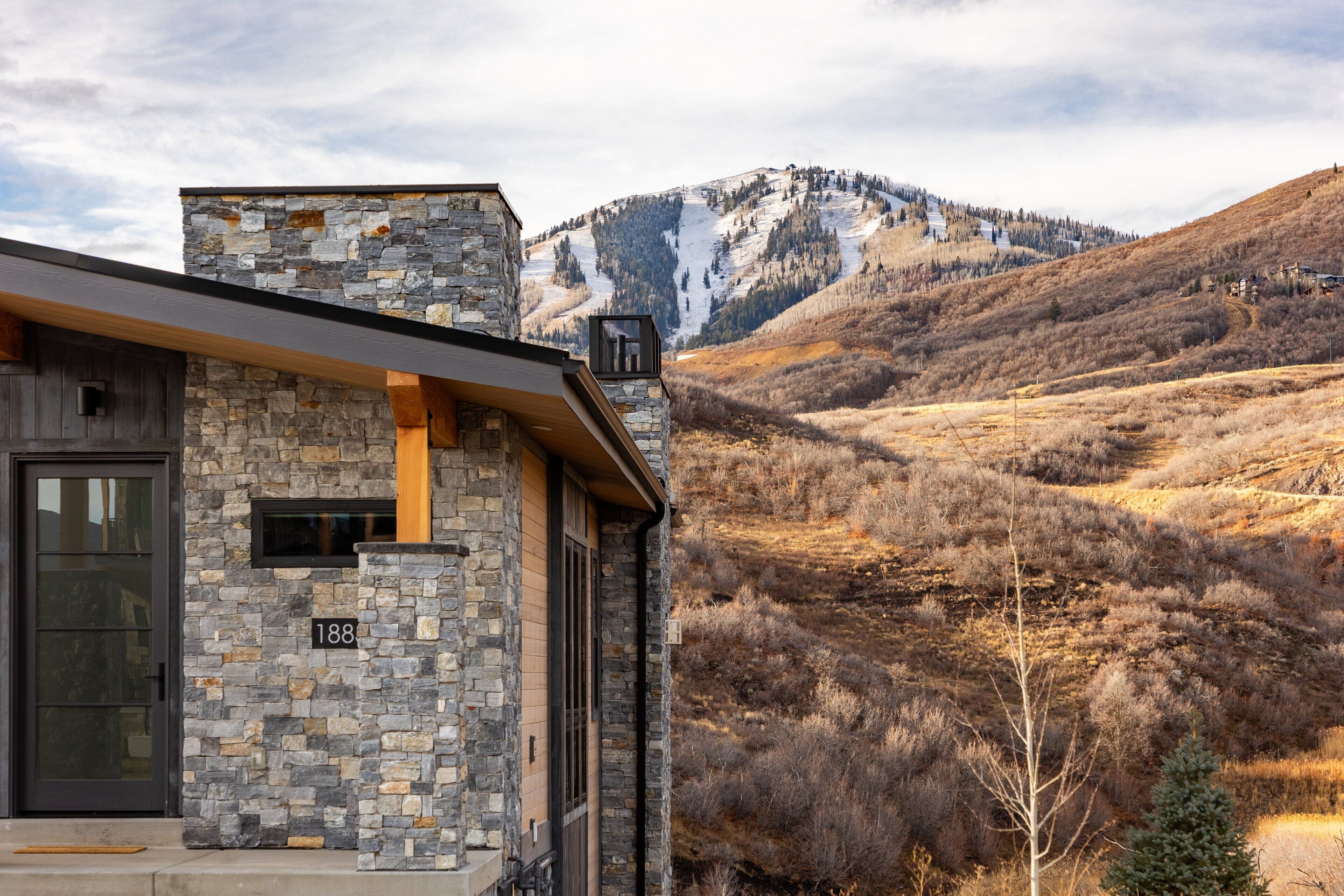 A stone building with a modern design, a visible number '188', and a mountainous landscape in the background.