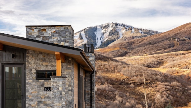 Ein Gebäude aus Stein mit modernem Design, einer sichtbaren Nummer '188' und einer Berglandschaft im Hintergrund.